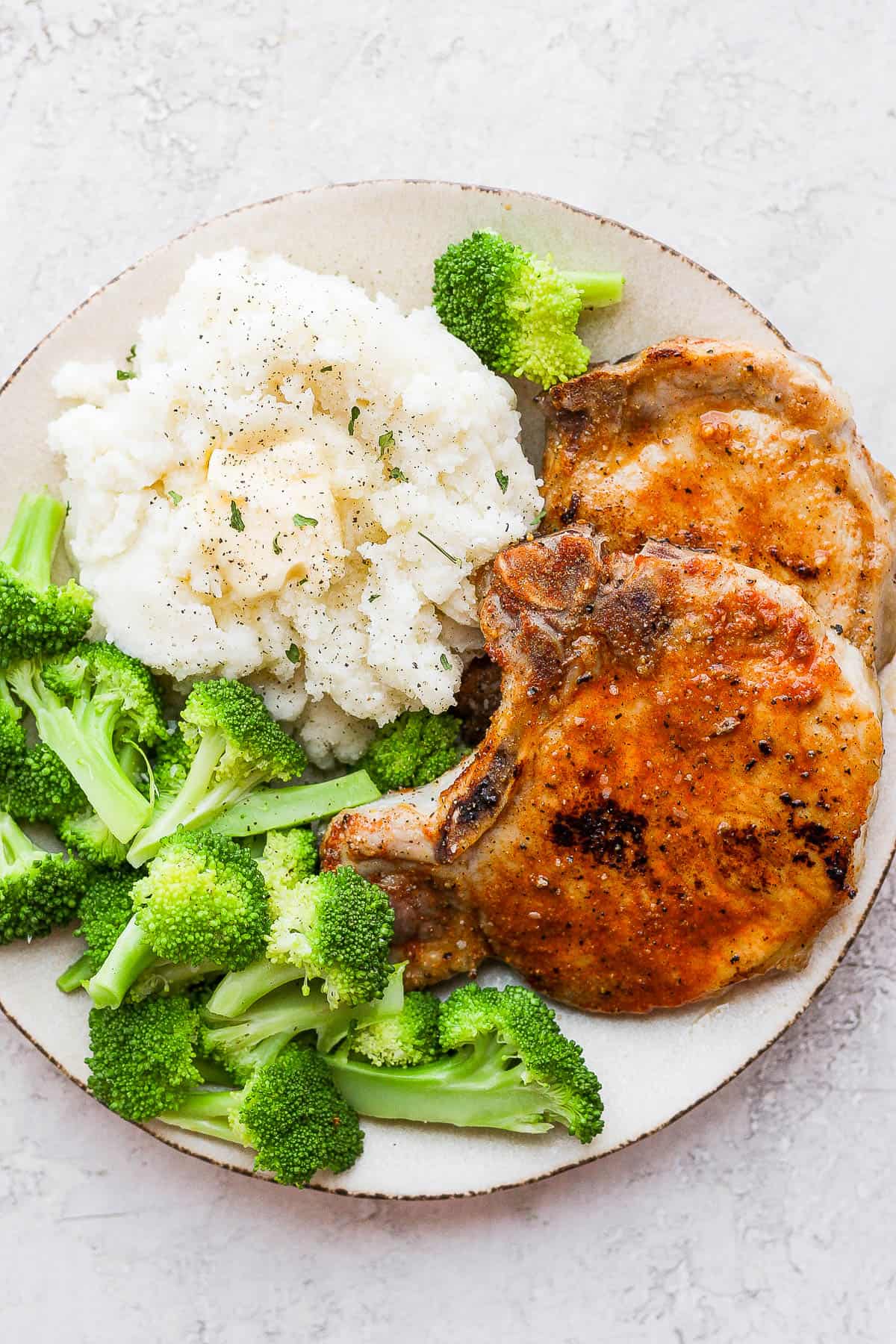 Baked pork chops, mashed potatoes, and broccoli on a plate. 