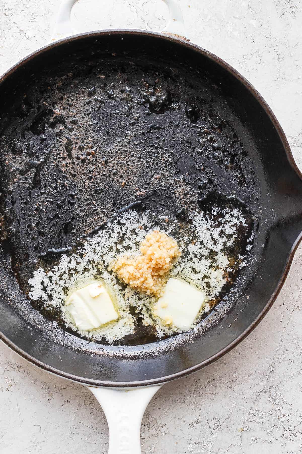 Butter melting with garlic in a cast iron skillet.