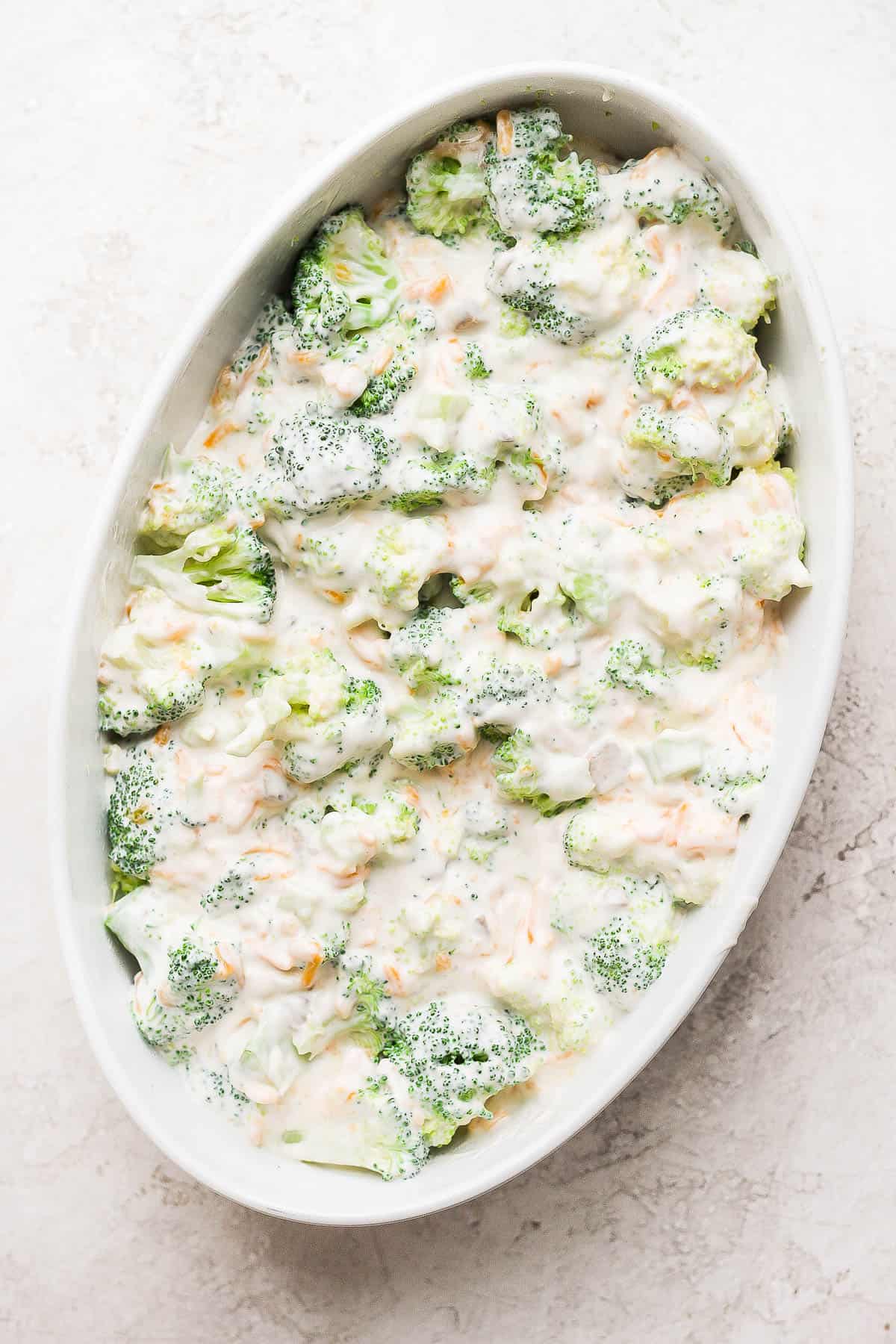 Steamed green beans in an oval casserole dish mixed with cream of mushroom soup, mayo, and cheddar cheese.