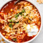 Bowl of chicken enchilada soup with sour cream and cheese on top.