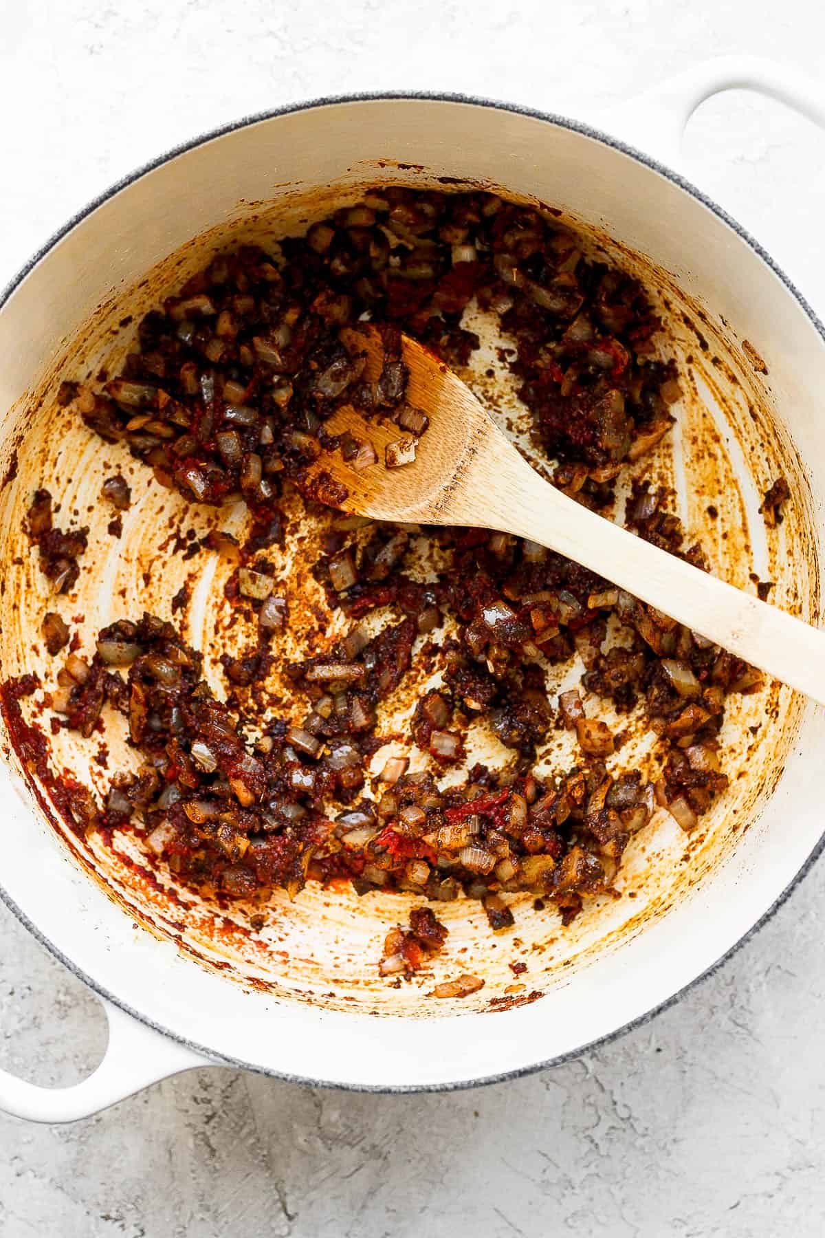 Garlic, onion, seasonings, and tomato paste all mixed together in a dutch oven.