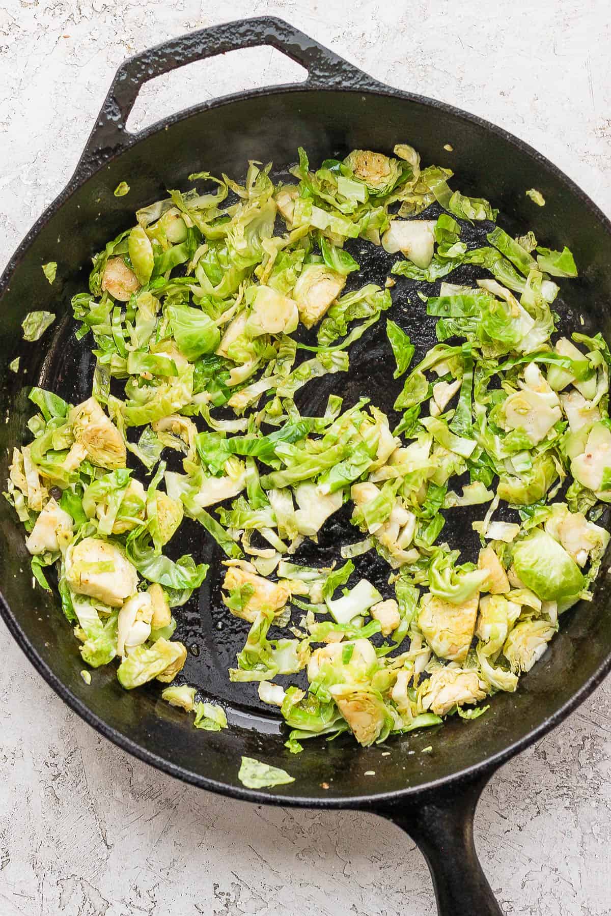 Shaved brussel sprouts and garlic in the skillet.