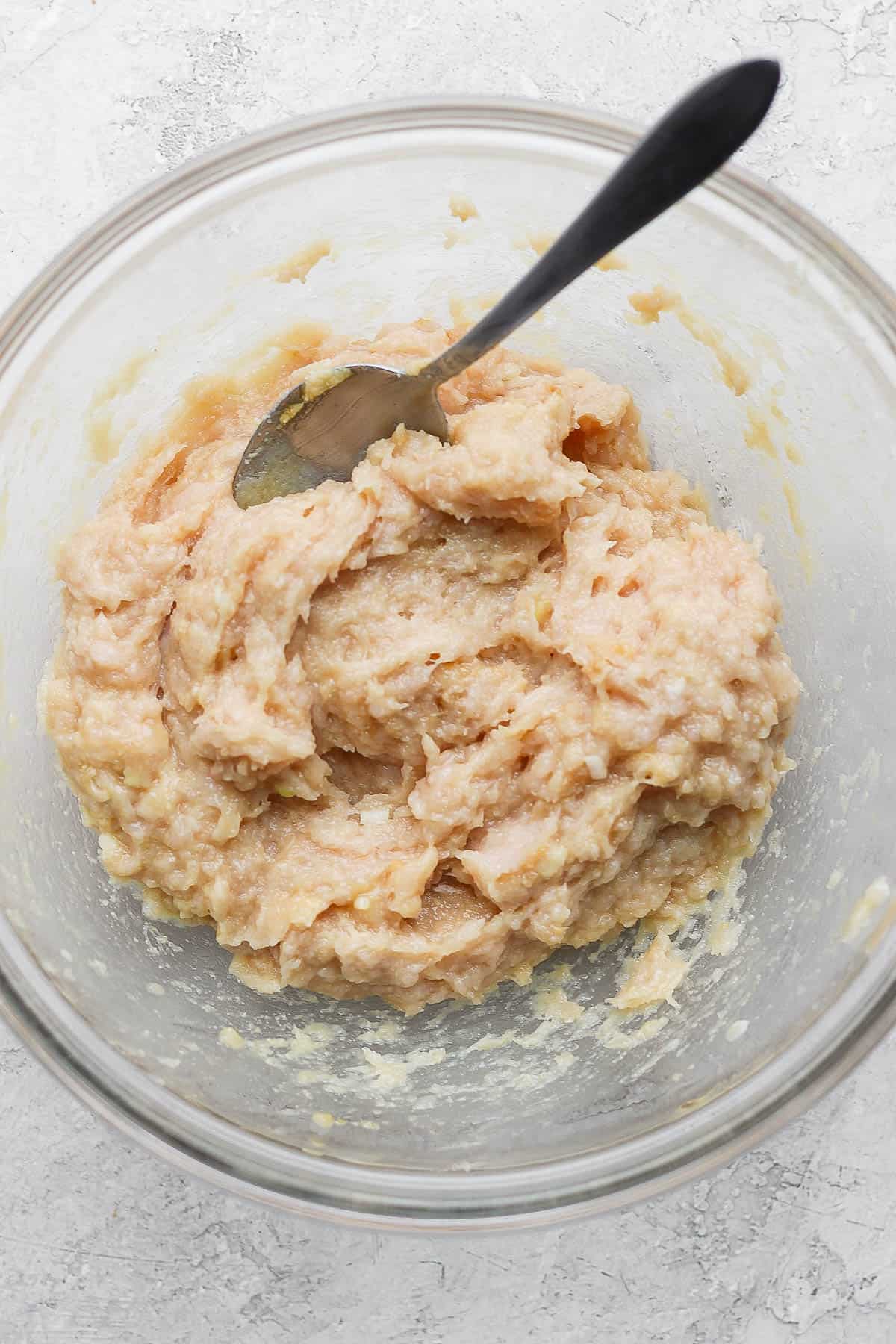 Meatball ingredients mixed together with a spoon in a mixing bowl.