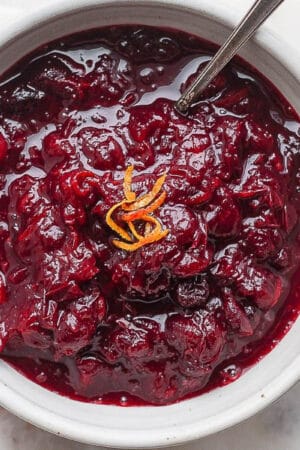 Bowl of cranberry orange sauce with spoon sticking out.