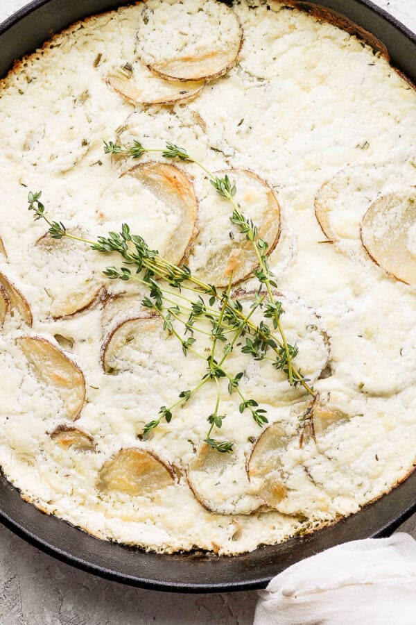 A cast iron skillet filled with goat cheese potatoes au gratin.