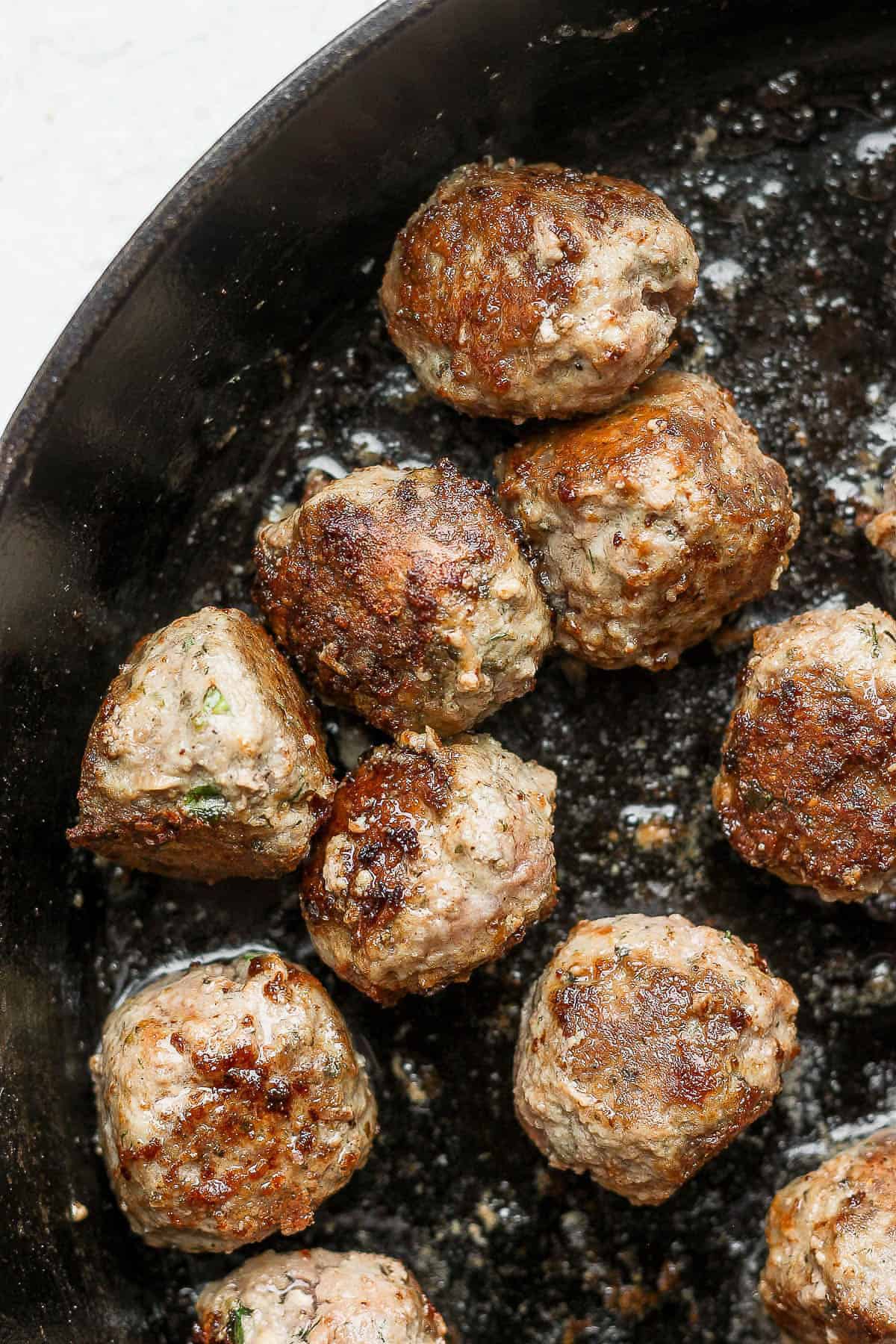 Seared meatballs in a cast iron skillet.