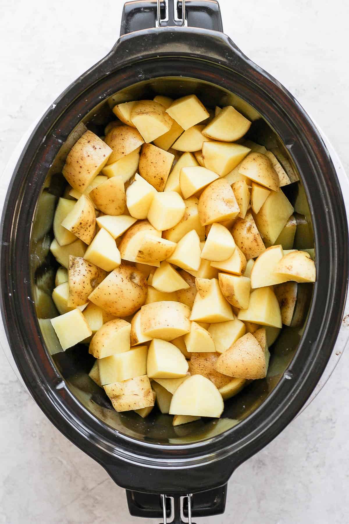 Cubed yukon gold potatoes inside a slow cooker. 