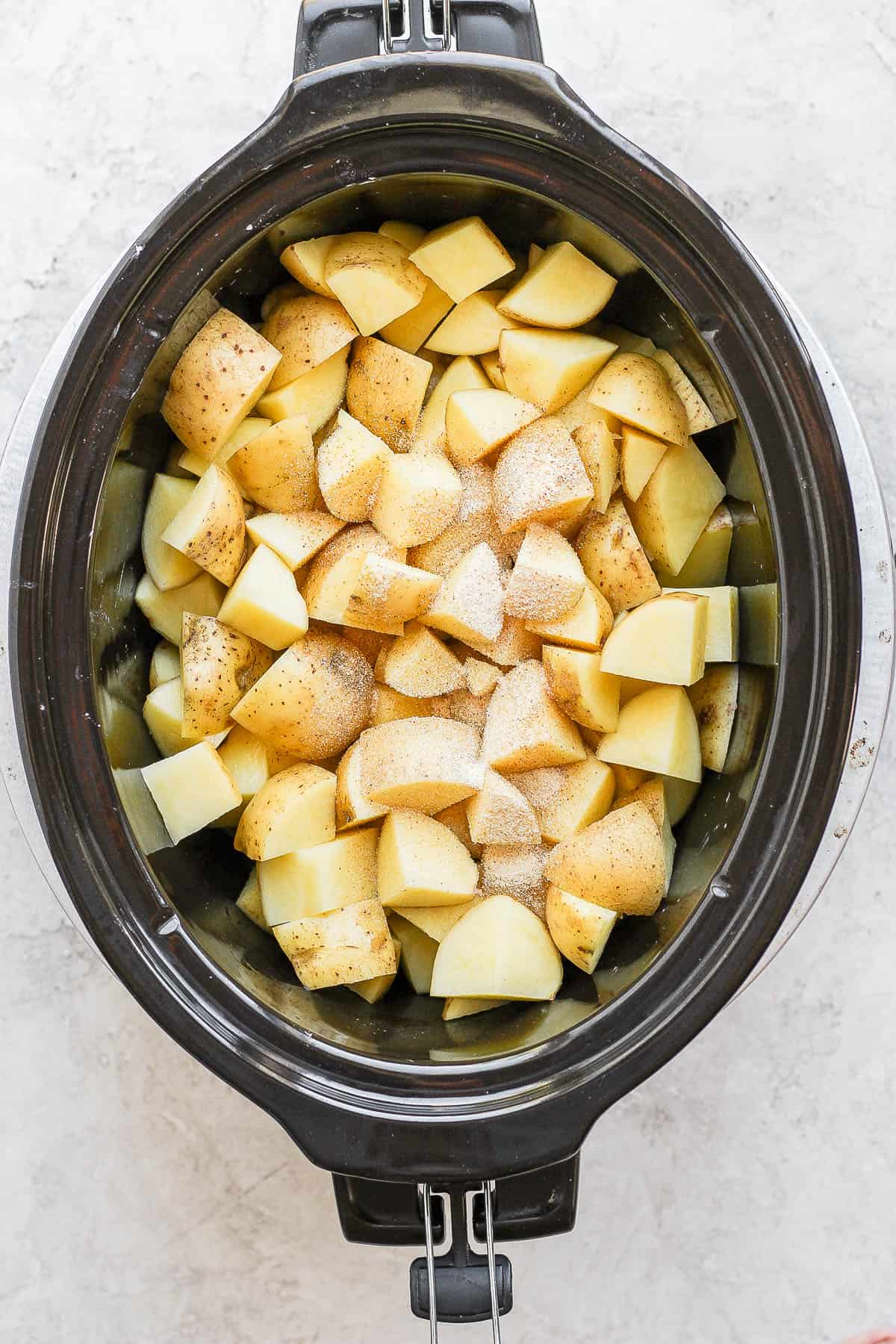 Garlic powder and onion powder sprinkled over the potatoes in the slow cooker.