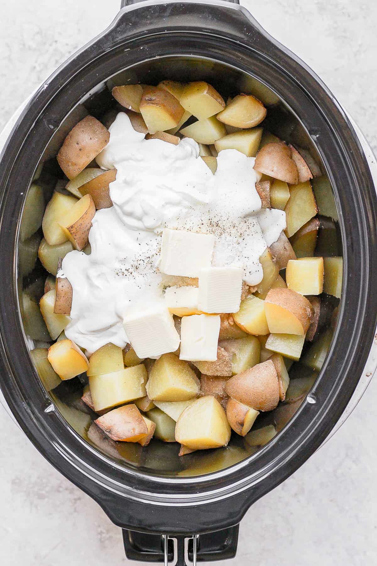 Sour cream, butter, ranch, greek yogurt, and milk added on top of the slow cooker potatoes. 