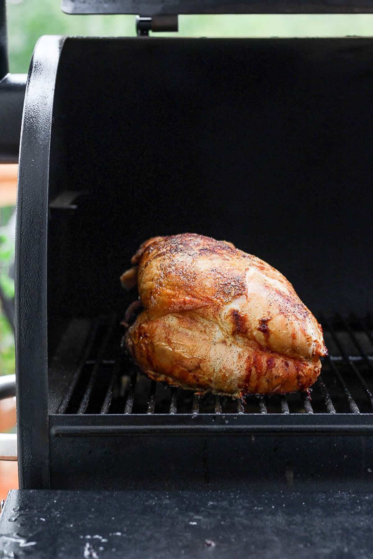 A cooked smoked turkey breast on a smoker.