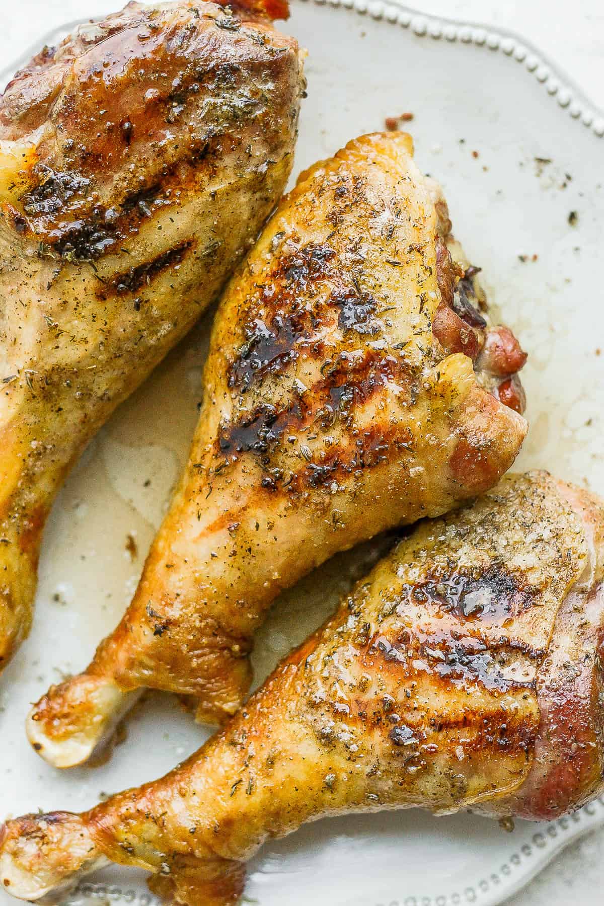 Smoked turkey legs on a plate after being seared on the grill.