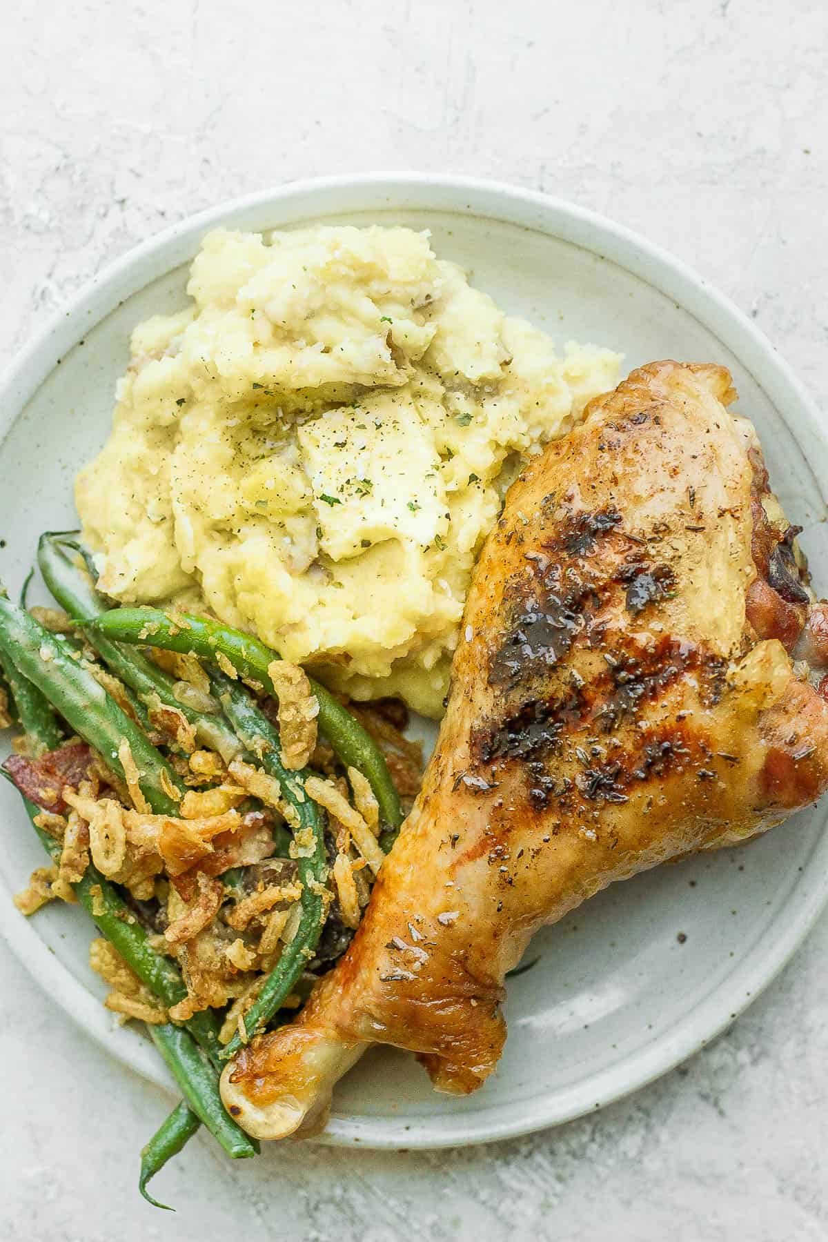 Smoked turkey legs with sides of mashed potatoes and green bean casserole.