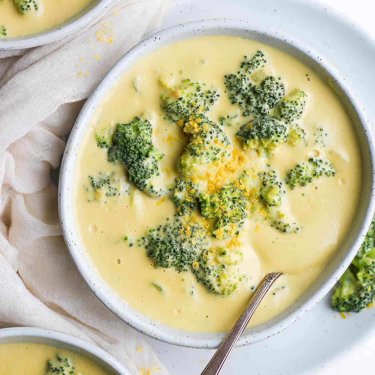 A bowl of dairy-free broccoli cheese soup with a spoon sticking out.