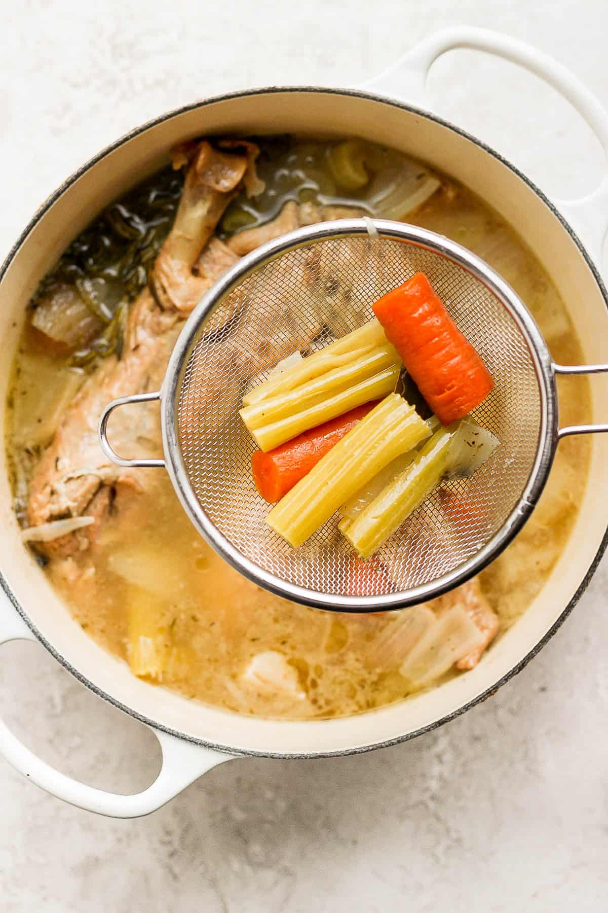 A mesh food strainer removing large food pieces from the pot.