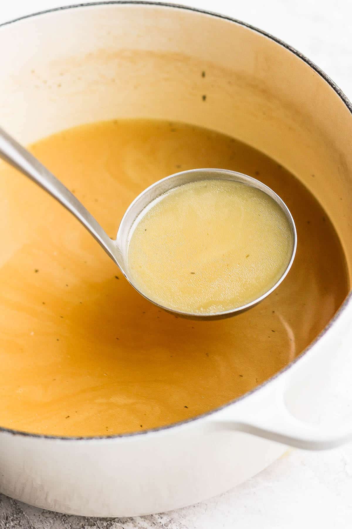 A ladle scooping turkey broth out of the pot.
