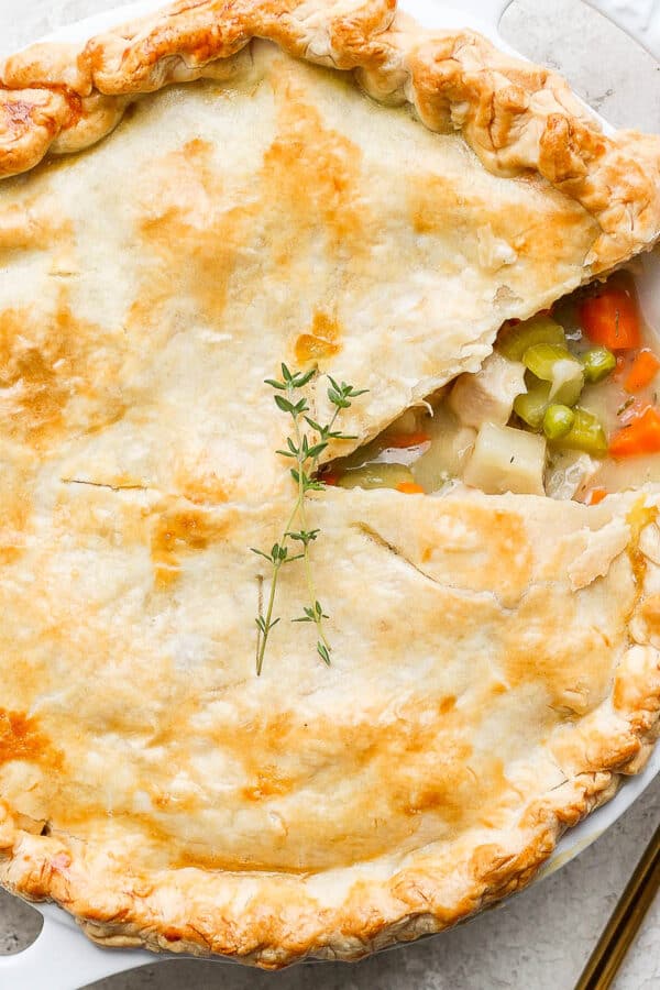 A turkey pot pie in a pie pan with a slice taken out and golden spoon next to it.