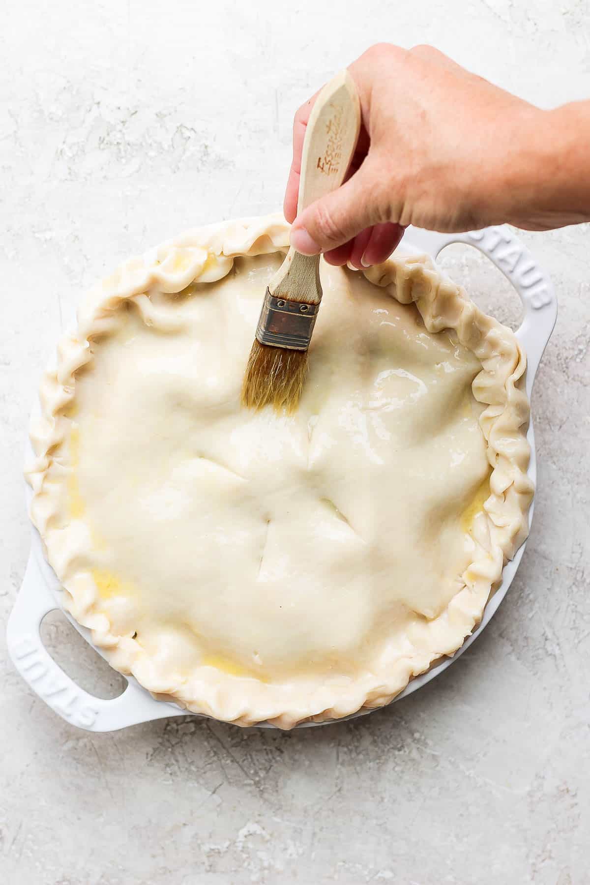 The egg wash being brushed on top of the pot pie.