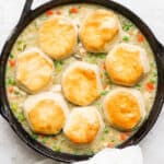 A cast iron skillet with turkey pot pie and biscuits inside.