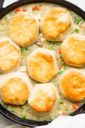 A cast iron skillet with turkey pot pie and biscuits inside.