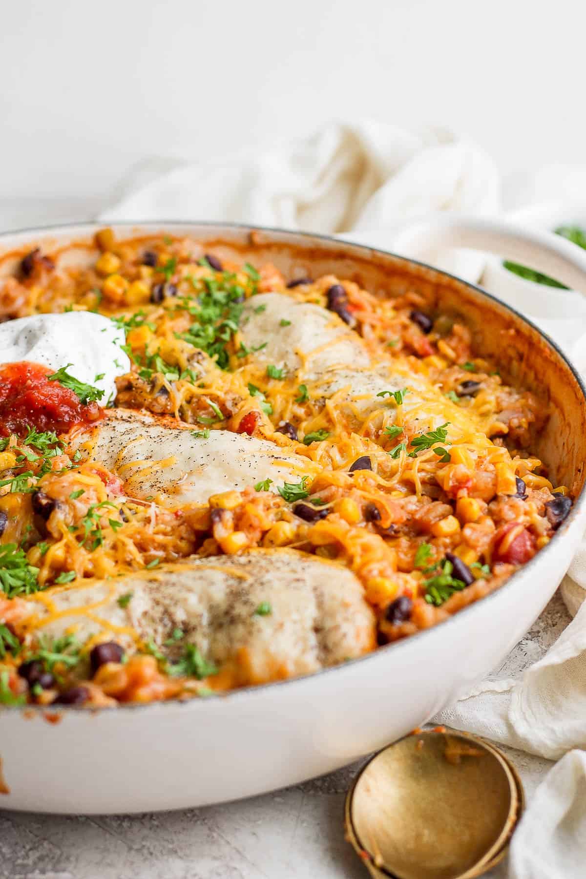 A baked salsa chicken and rice with toppings in the skillet.