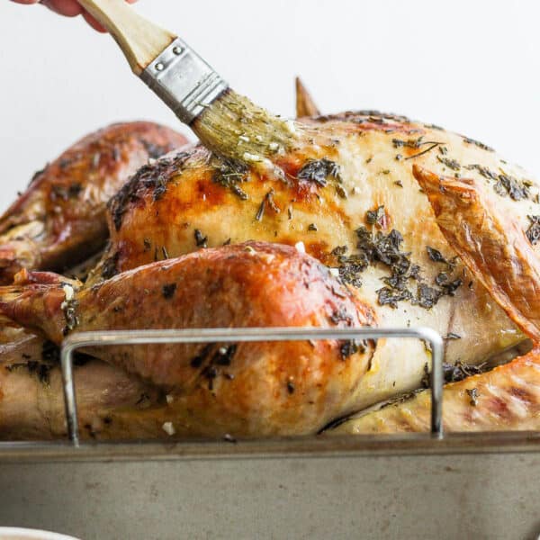 Someone basting a turkey with a brush.