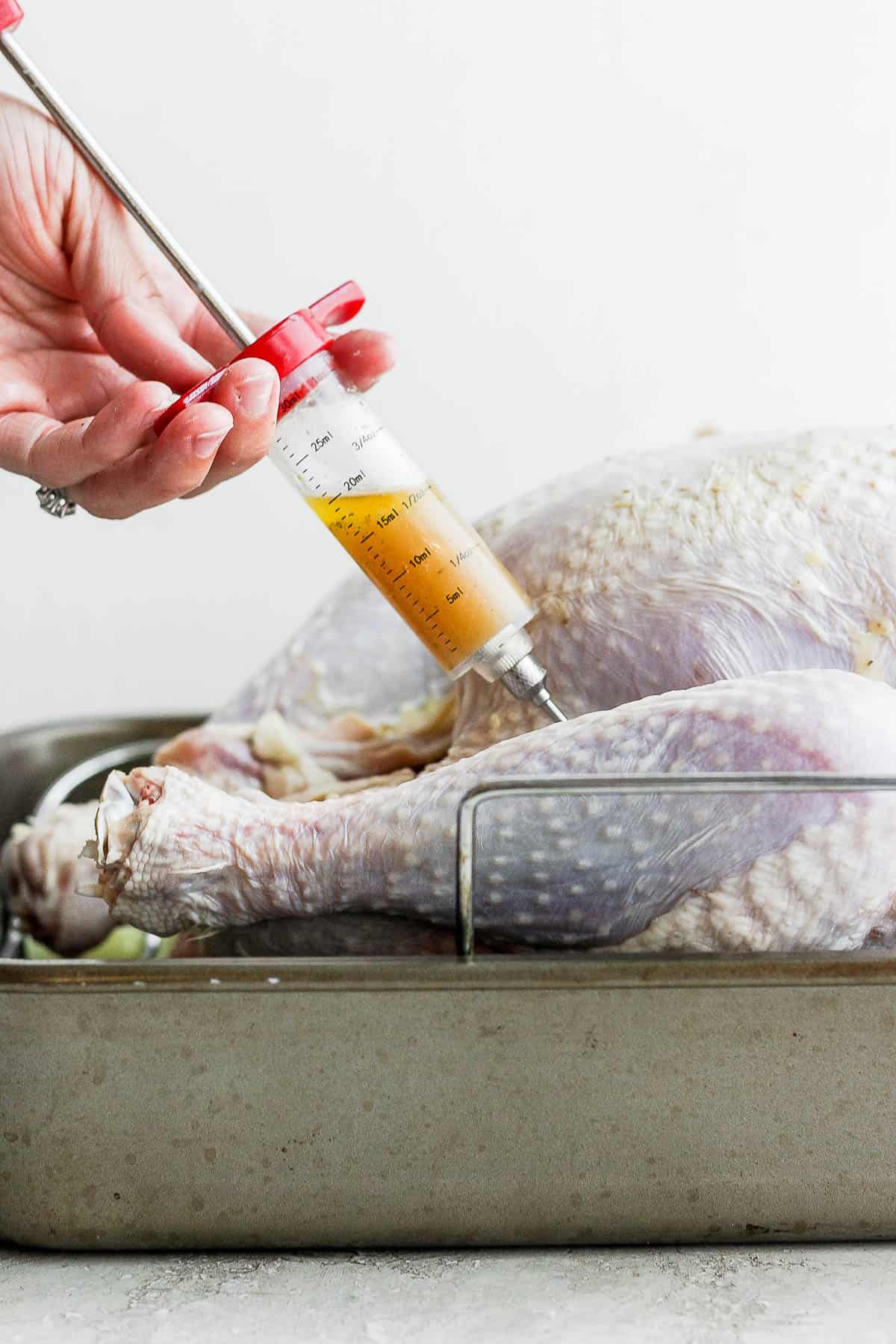 The melted butter mixture being injected into the turkey thigh.