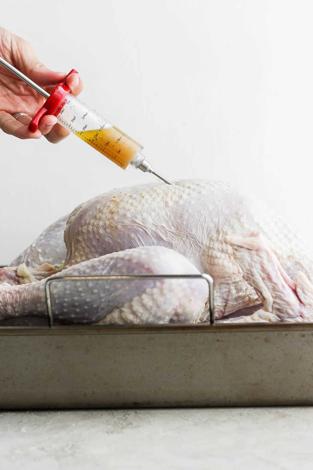 A turkey breast being injected with the melted butter mixture.