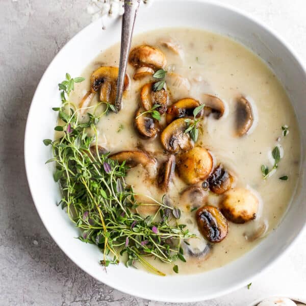 Bowl of dairy free cream of mushroom soup with sauteed mushrooms and fresh thyme on top.