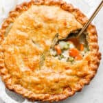 A chicken pot pie with a portion scooped out and a spoon sticking out.