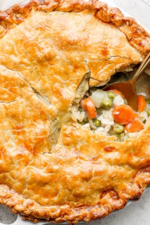 A chicken pot pie with a portion scooped out and a spoon sticking out.