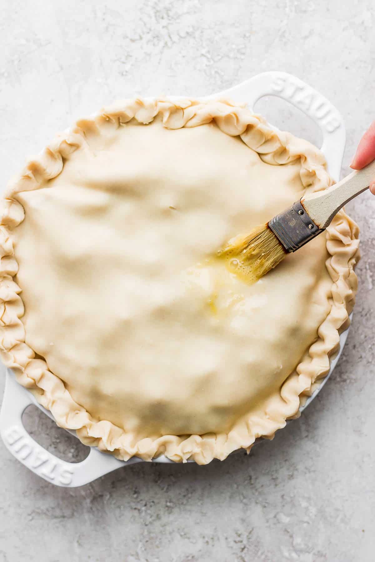 The egg wash being brushed on the top of the crust after the filling was added.