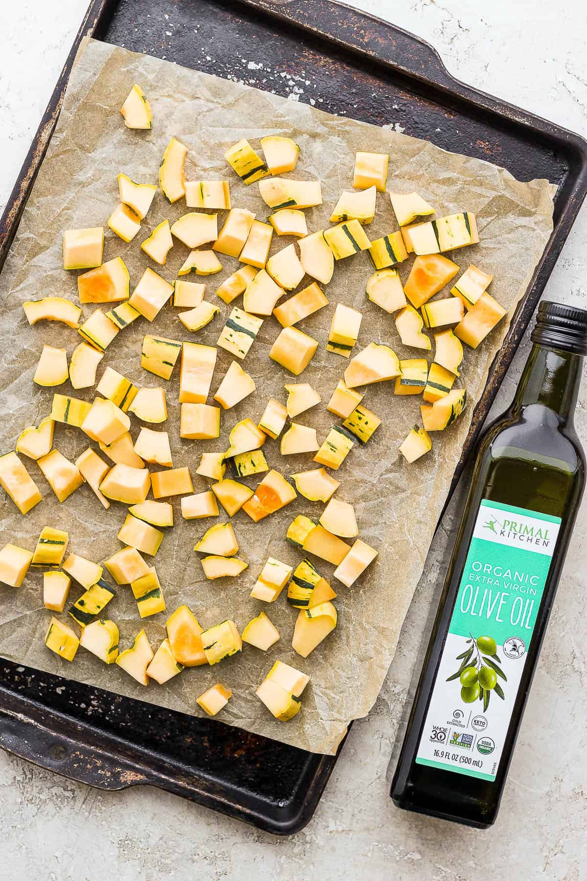 Cubed delicata squash on a parchment-lined baking sheet.