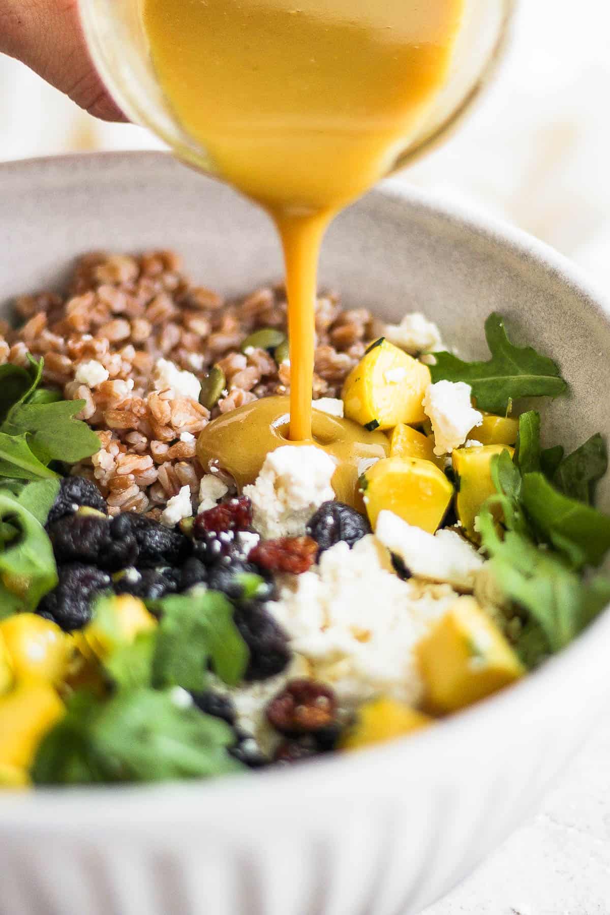 The dressing being poured over the farro salad.