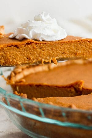Someone lifting a piece of gluten free pumpkin pie out of a pie pan.
