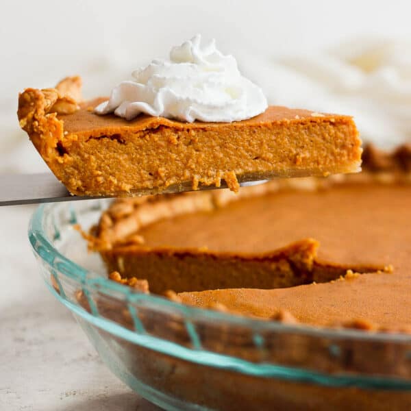 Someone lifting a piece of gluten free pumpkin pie out of a pie pan.