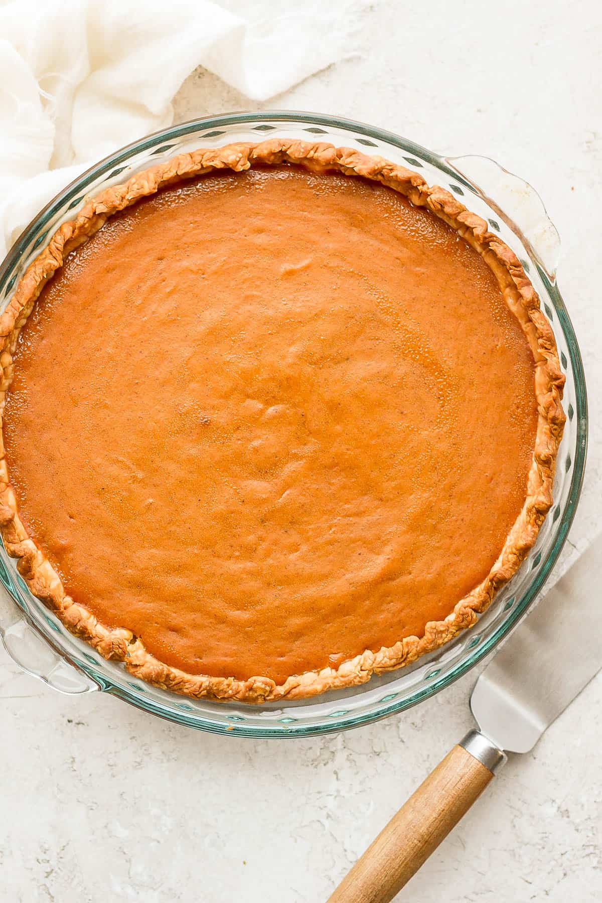 A fully cooked gluten free pumpkin pie in a glass pie pan.