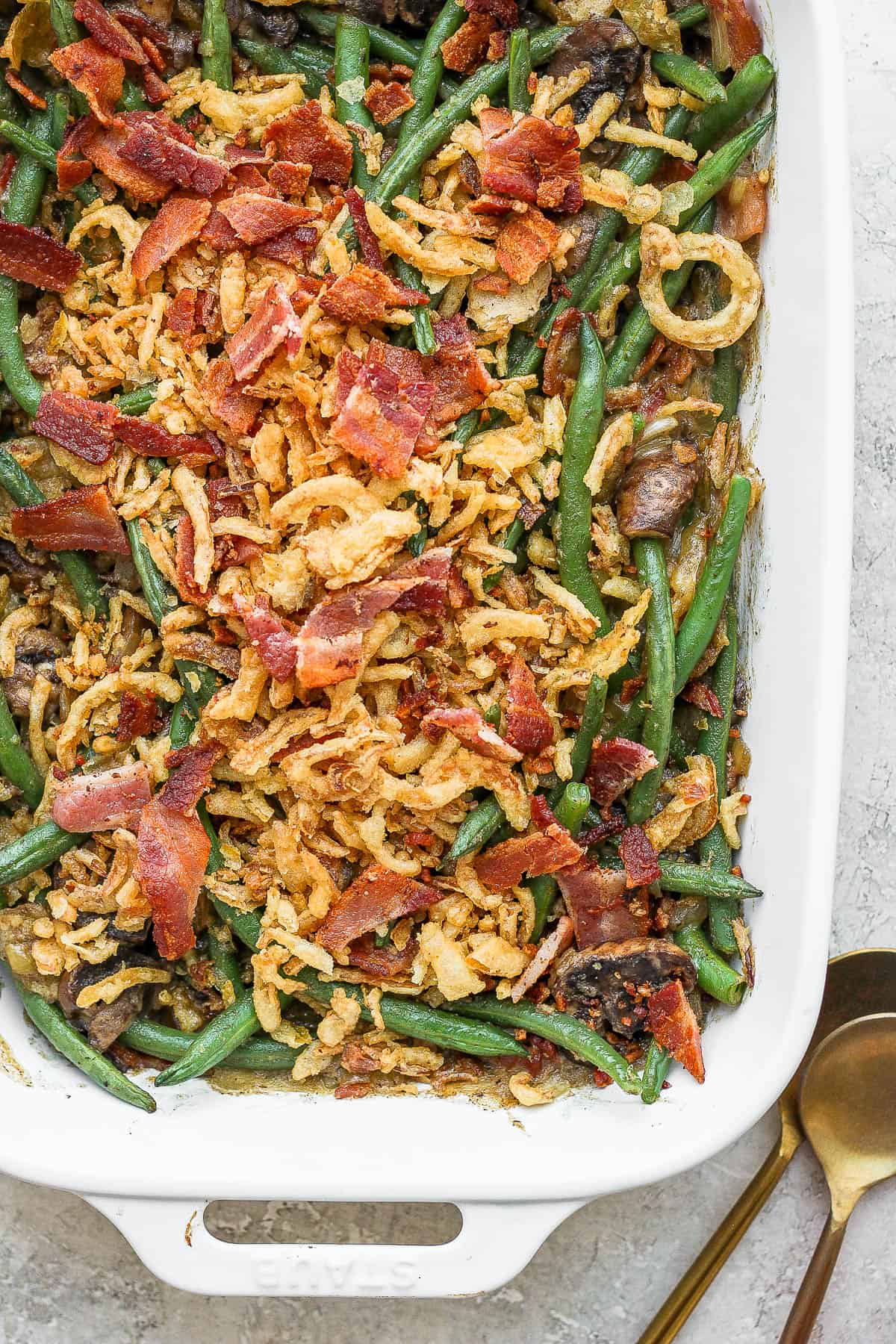 Close up of a green bean casserole with bacon in a casserole dish.