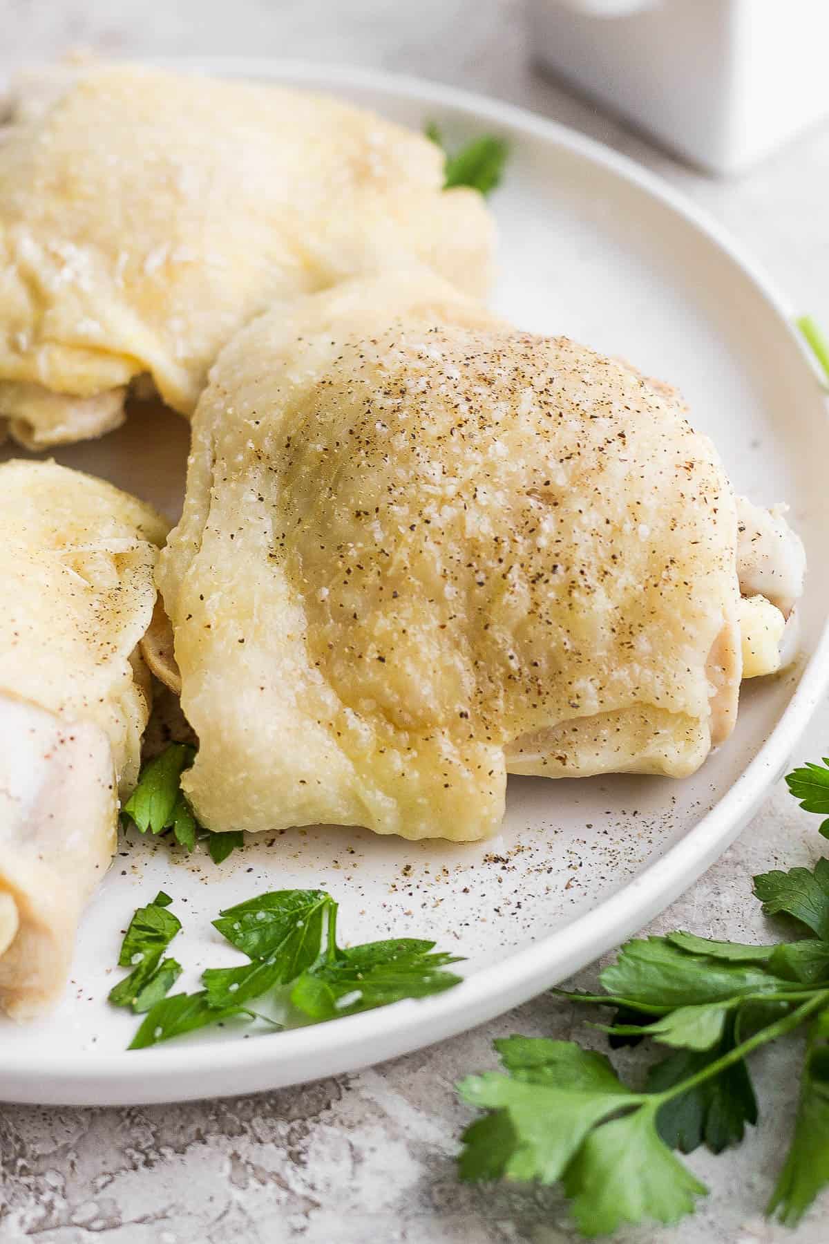 A boiled chicken thigh seasoned with salt and pepper on a plate. 