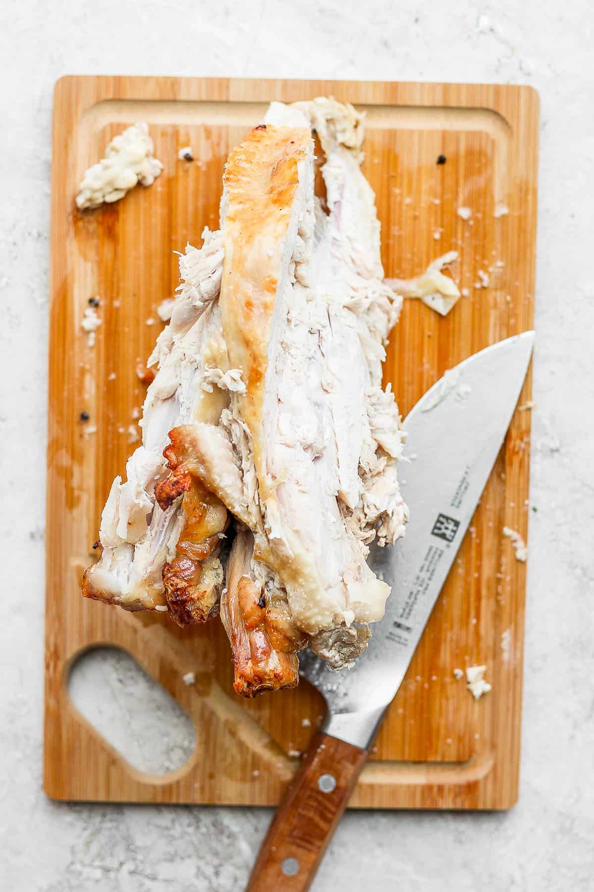 The remaining turkey carcass or bones on the cutting board with the knife.