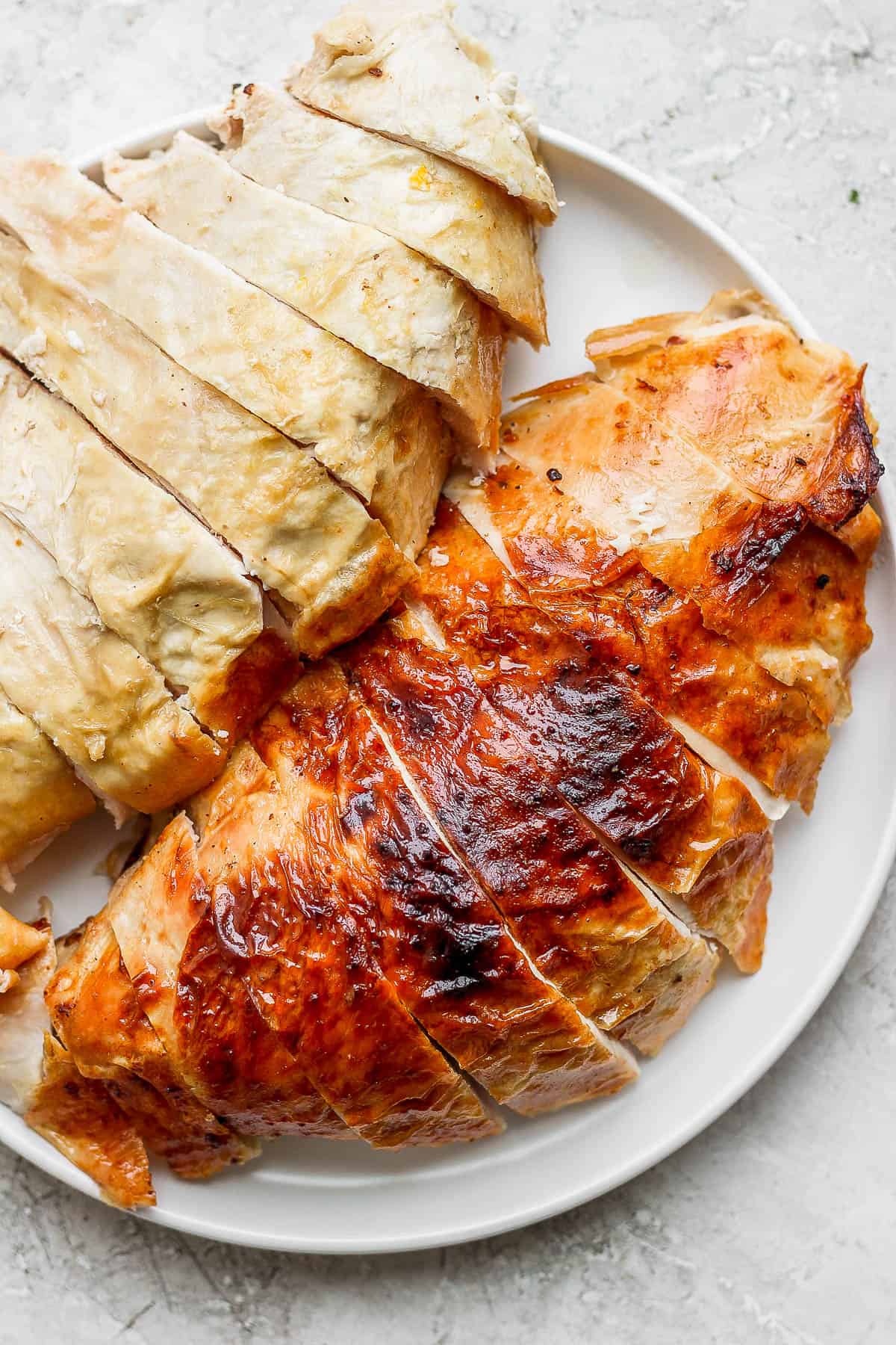 Sliced turkey breasts on a white plate.