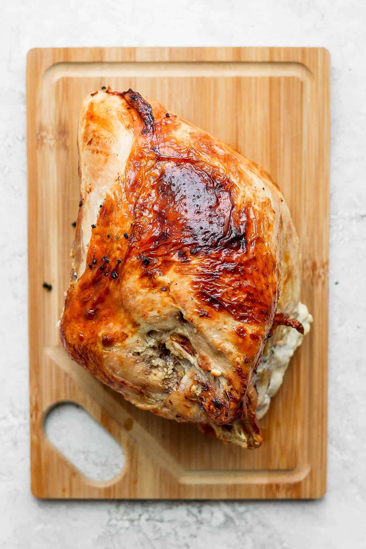 A fully cooked turkey breast on a cutting board.