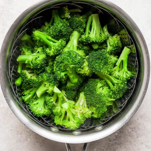 Steamed broccoli in a saucepan with a steamer basket inside.