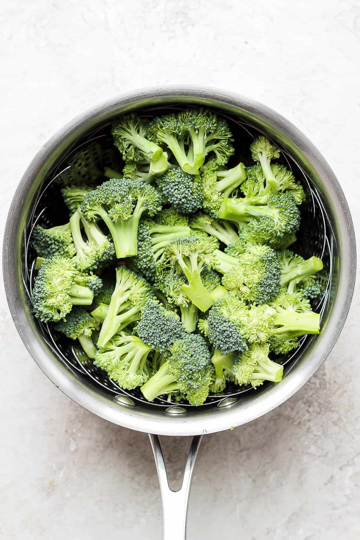 Uncooked broccoli in a steamer basket.