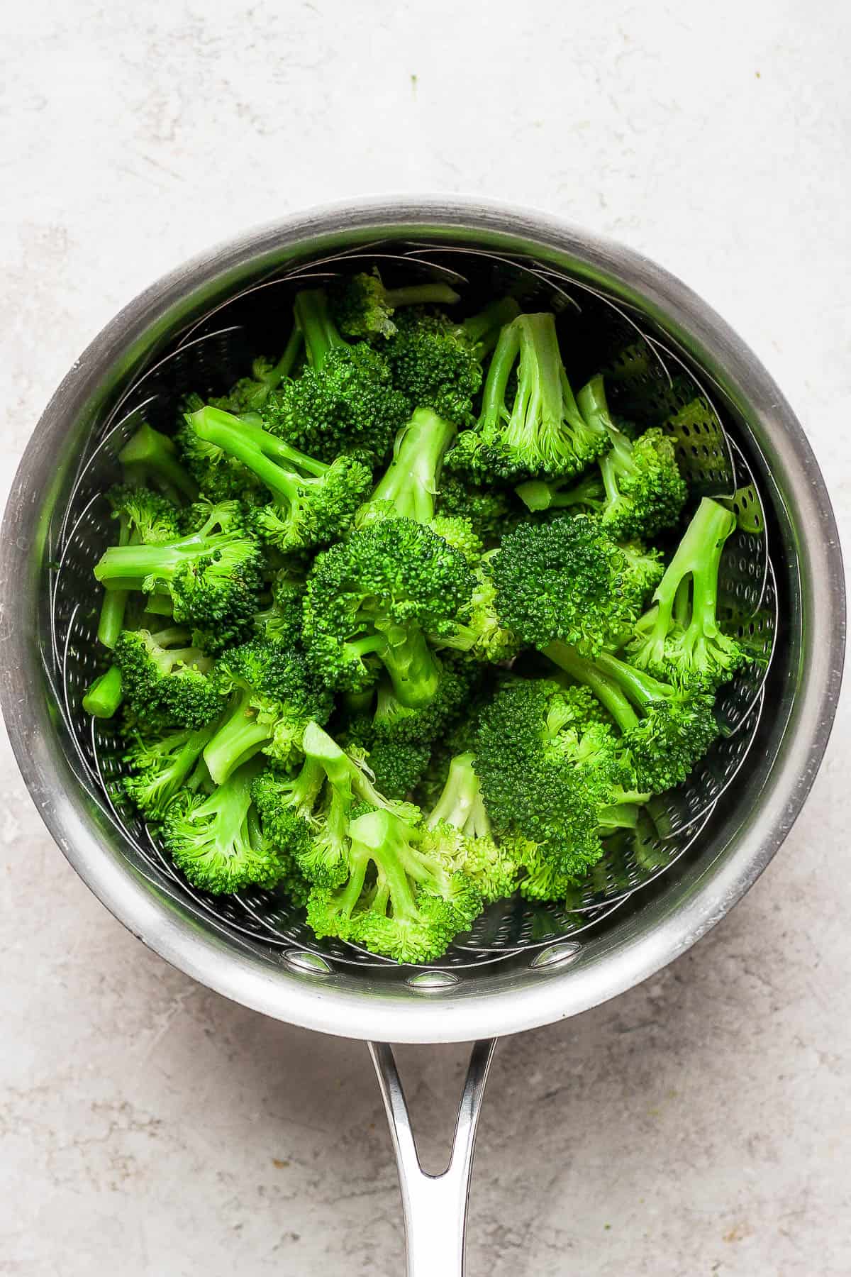 Steamed broccoli in a steamer basket.