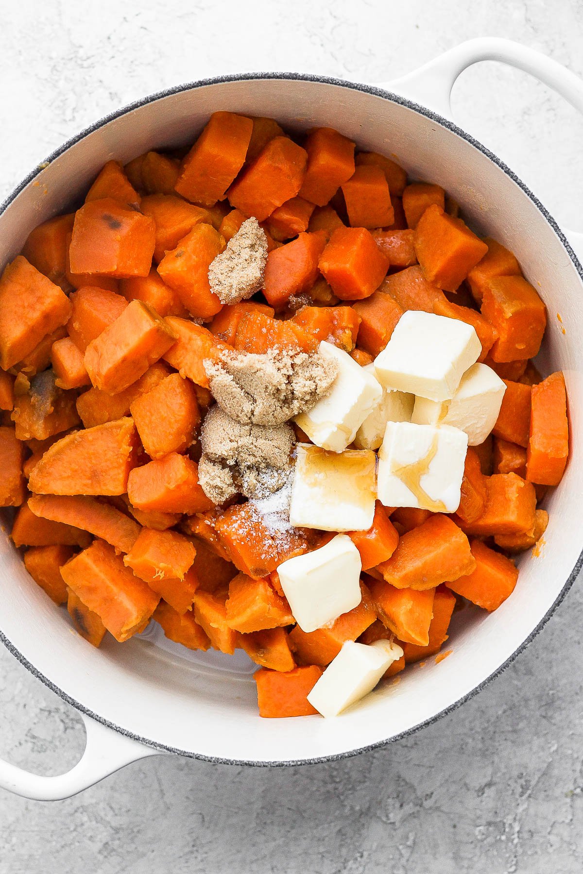 Boiled sweet potatoes drained and placed back into the pot with butter, brown sugar, cream, and syrup.