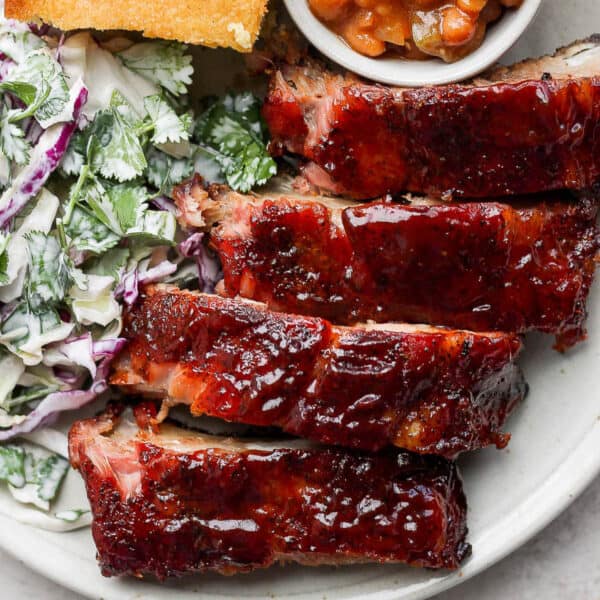 A plate of ribs with coleslaw, cornbread and baked beans.