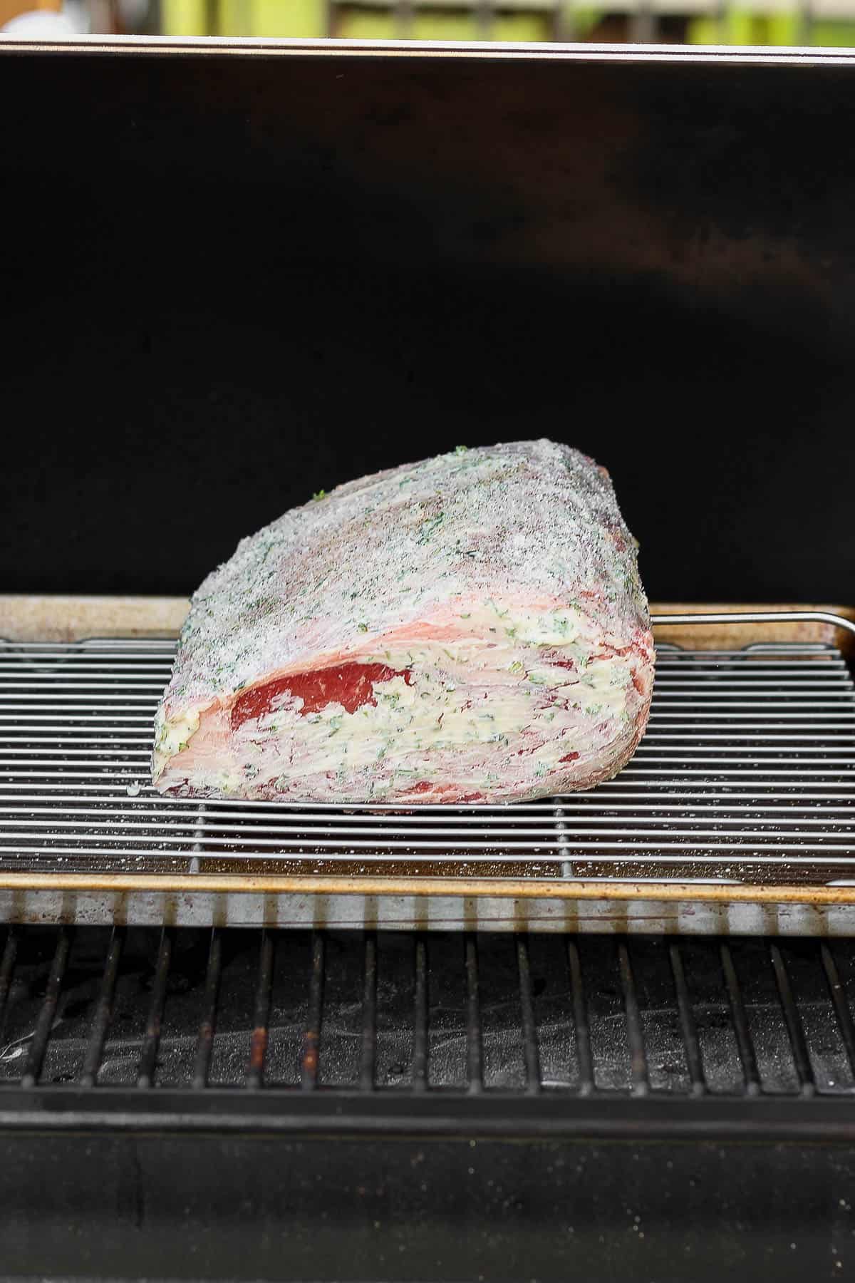 Prime rib on a baking sheet with a wire rack on the smoker.