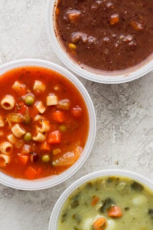 Top shot of three plastic containers with three different soups in them.
