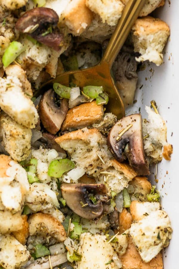 Close up of sourdough stuffing in a baking dish with a golden spoon.