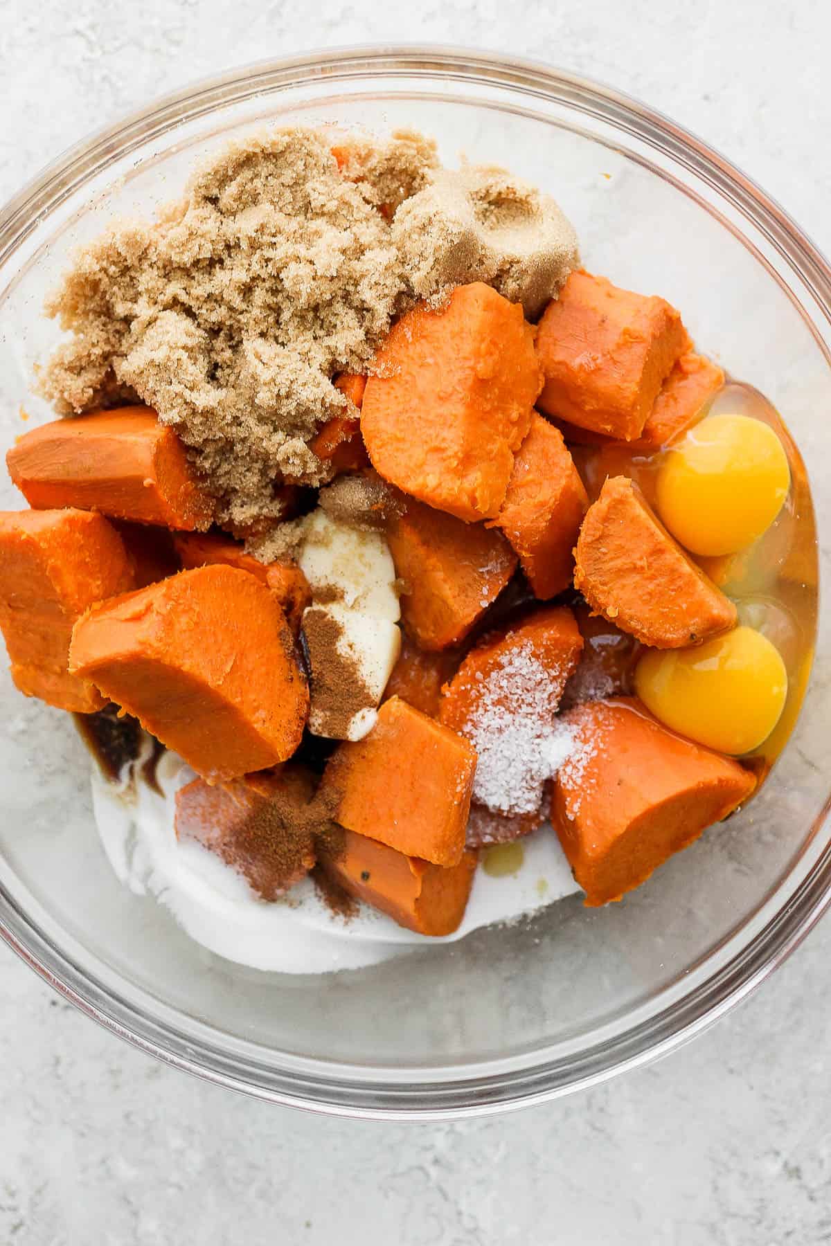 Boiled and cubed Sweet potatoes, brown sugar, eggs, salt, butter, full fat coconut milk, maple syrup, cinnamon, nutmeg, and vanilla in a mixing bowl.